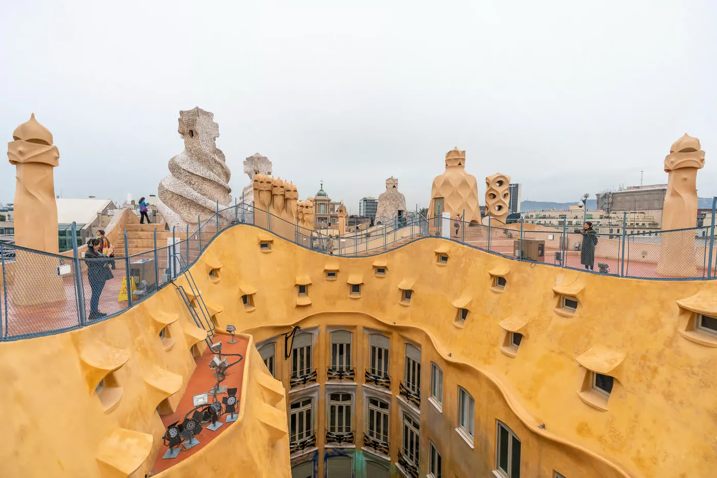 Visitors cross La Pedrera rooftop among sculpted chimneys and curved roof forms.