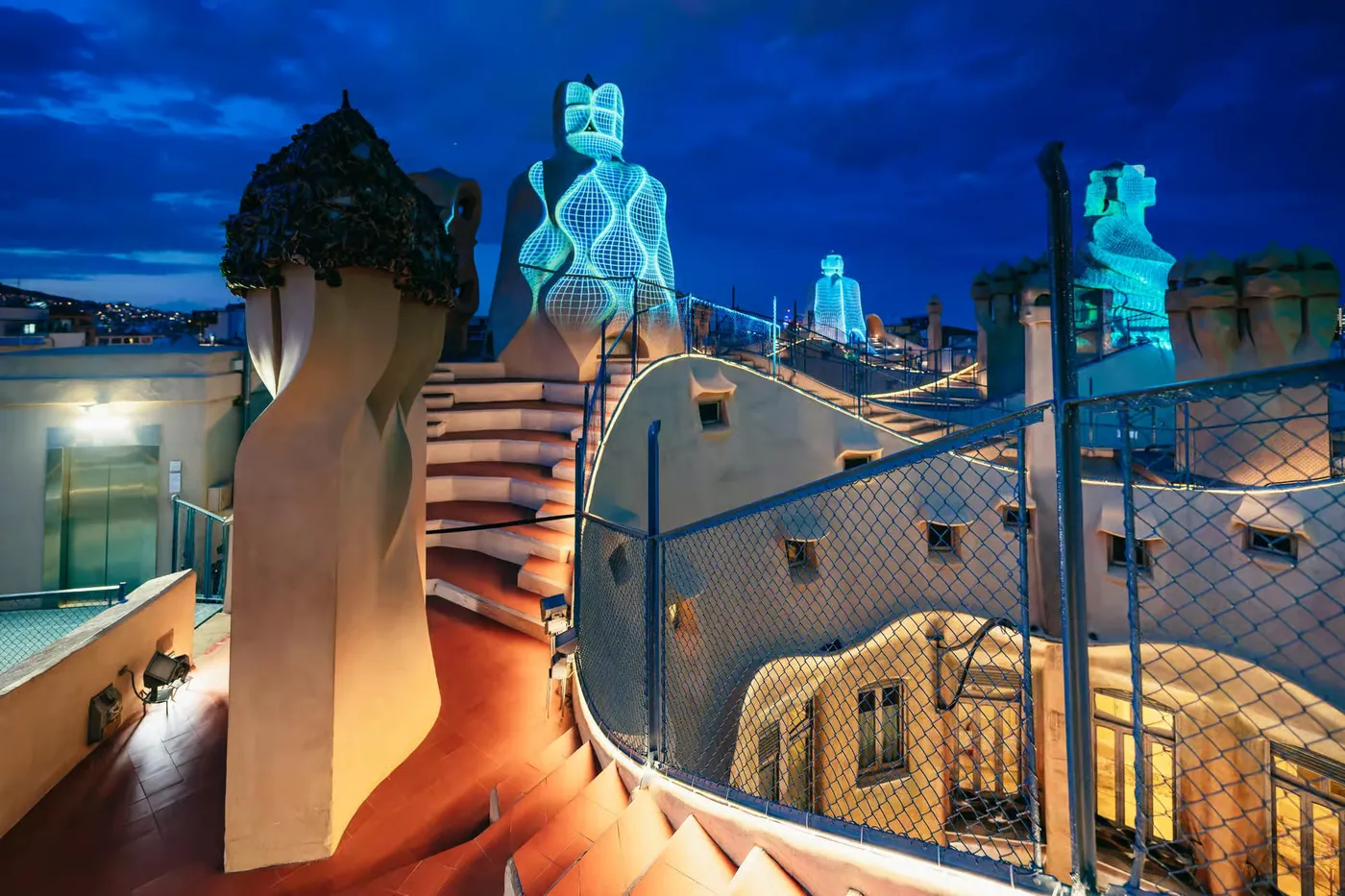 Blue projections illuminate La Pedrera rooftop chimneys during the night show.